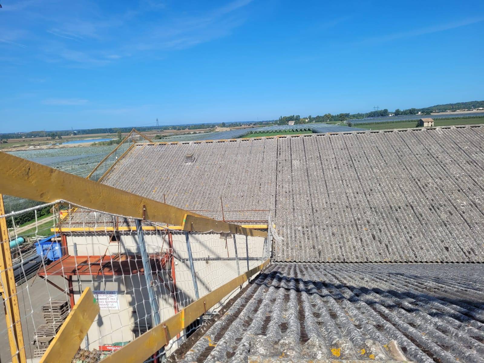 Réalisation de travaux de désamiantage toiture agricole à Perpignan avec remplacement par panneaux sandwich et pose d'exutoires de fumée conformes aux normes INRS.